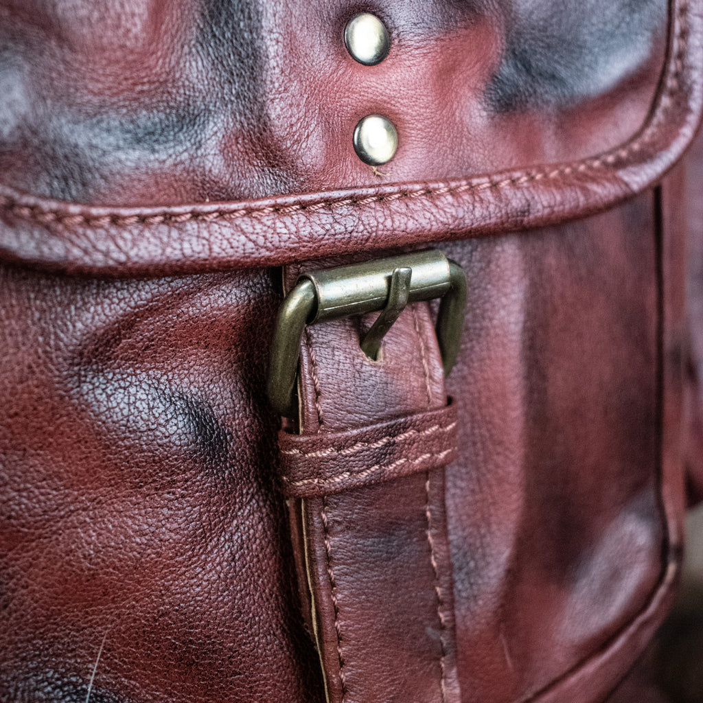 The buckle of a brown leather backpack