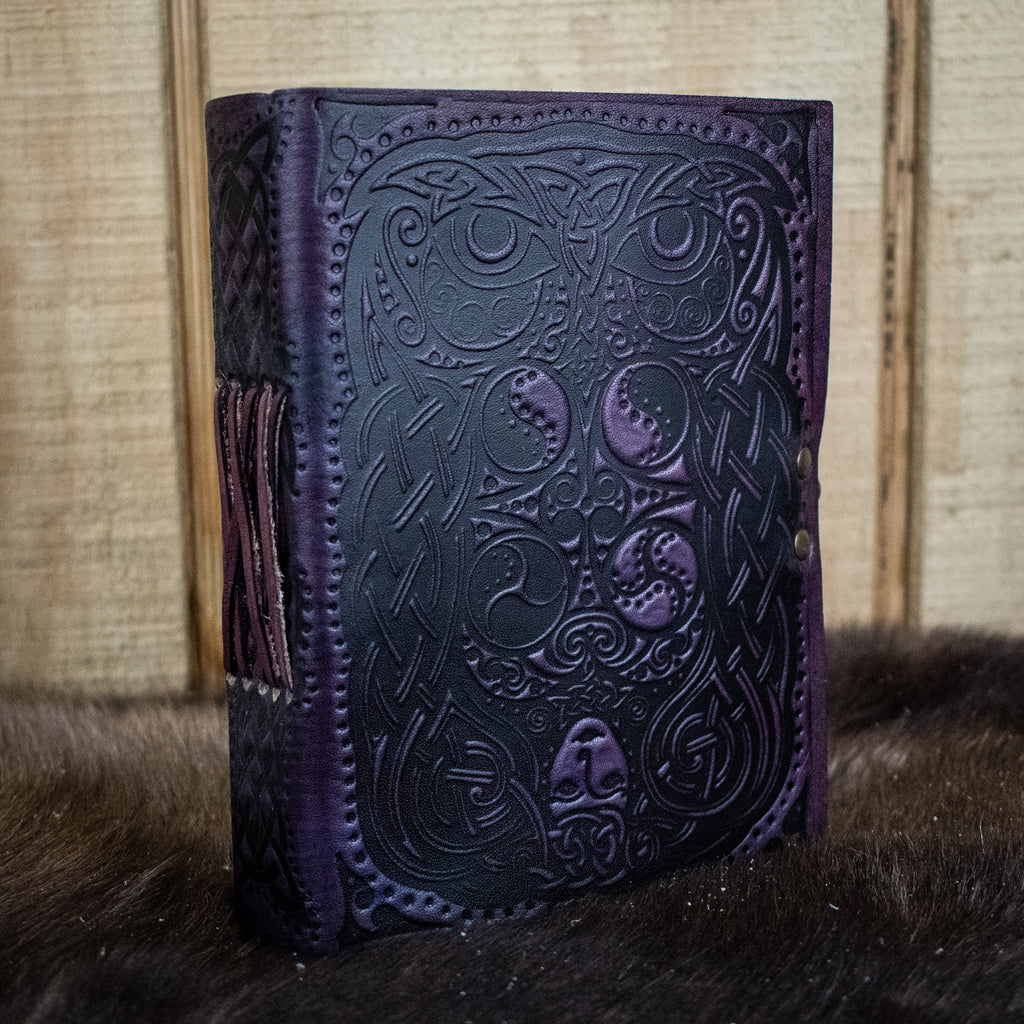 A purple leather journal featuring an owl and a woman