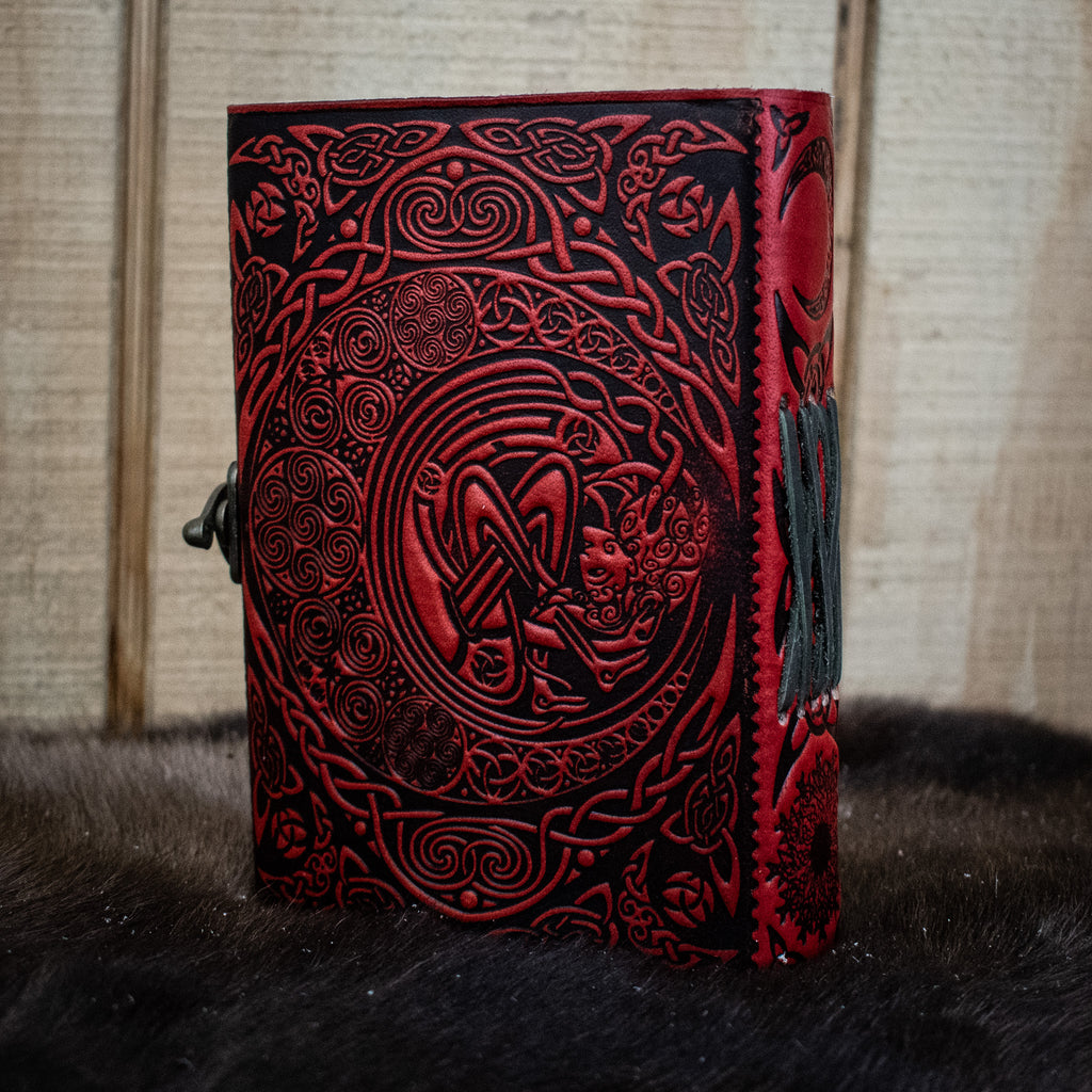 A red leather journal featuring a Celtic sun and moon