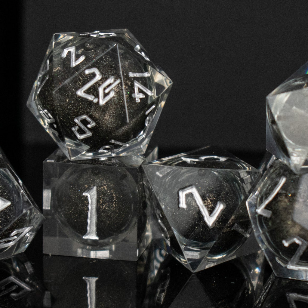 Black liquid and glitter inside of clear sharp resin dice with white numbers in a Nordic font