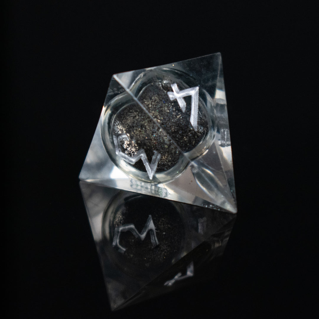 Black liquid and glitter inside of clear sharp resin dice with white numbers in a Nordic font