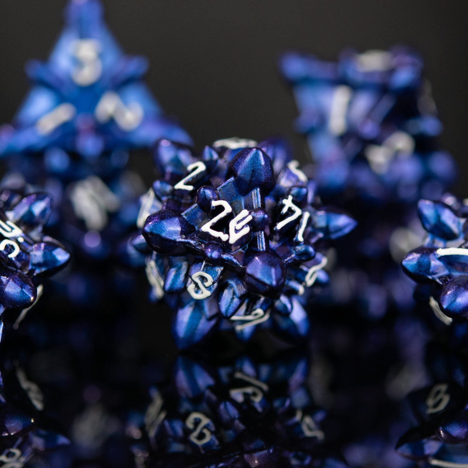blue metal d20 dice with embossed white numbers, designed to resemble asteroid shapes, displayed on a reflective surface.