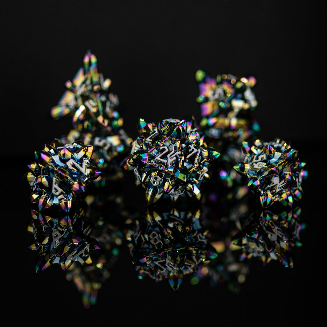 A set of metal dnd dice with embossed white numbers, featuring an iridescent oil slick, asteroid-like finish, displayed on a reflective surface.