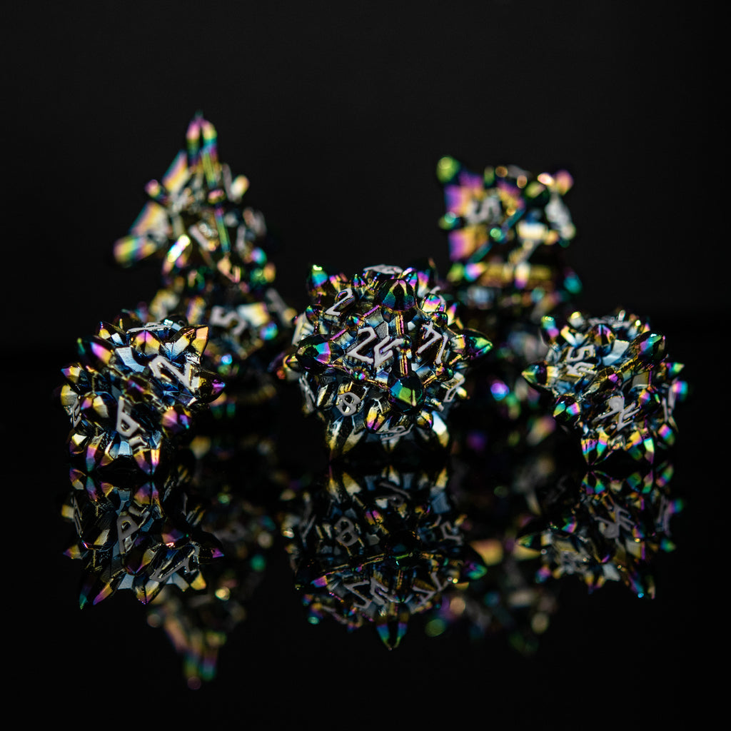 A set of metal dnd dice with embossed white numbers, featuring an iridescent oil slick, asteroid-like finish, displayed on a reflective surface.