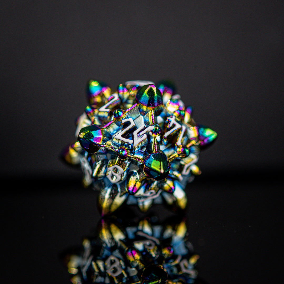 A set of metal dnd dice with embossed white numbers, featuring an iridescent oil slick, asteroid-like finish, displayed on a reflective surface.