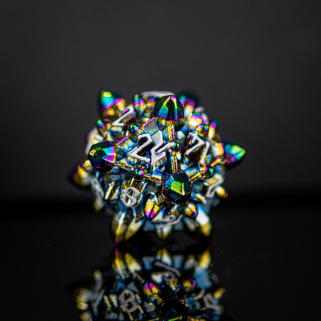 A set of metal dnd dice with embossed white numbers, featuring an iridescent oil slick, asteroid-like finish, displayed on a reflective surface.