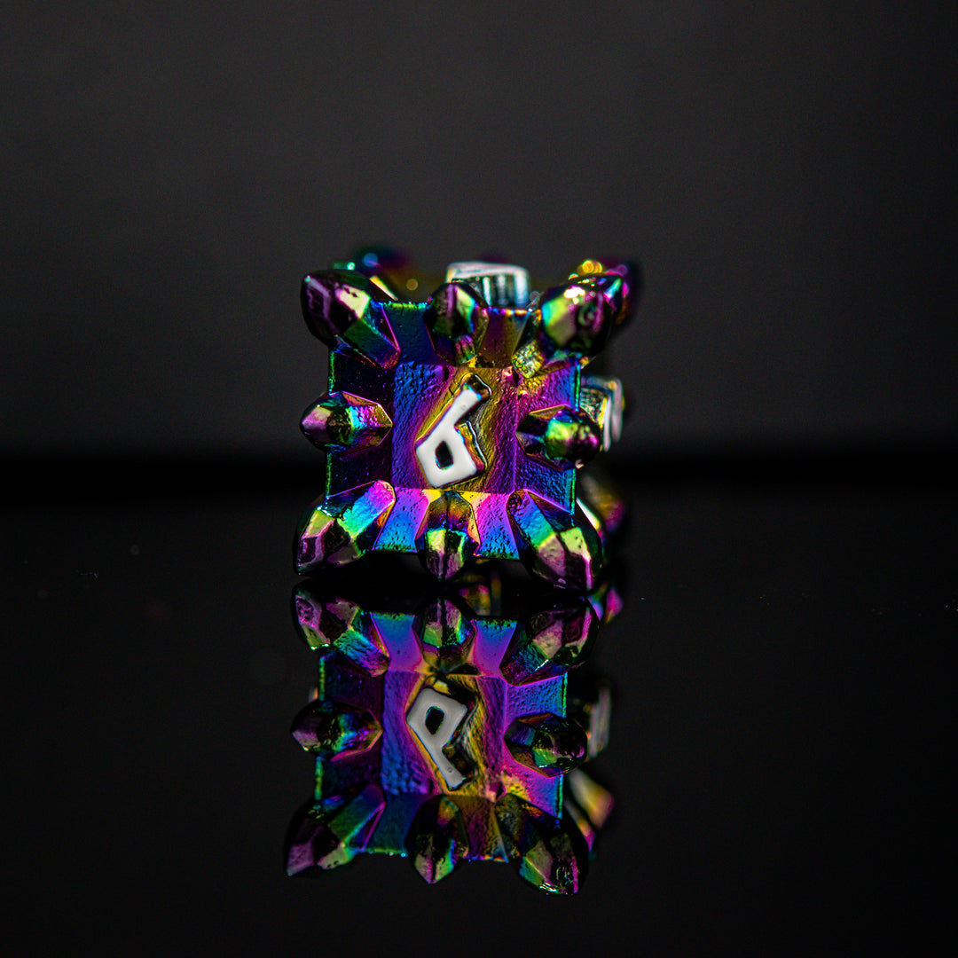 A set of metal dnd dice with embossed white numbers, featuring an iridescent oil slick, asteroid-like finish, displayed on a reflective surface.
