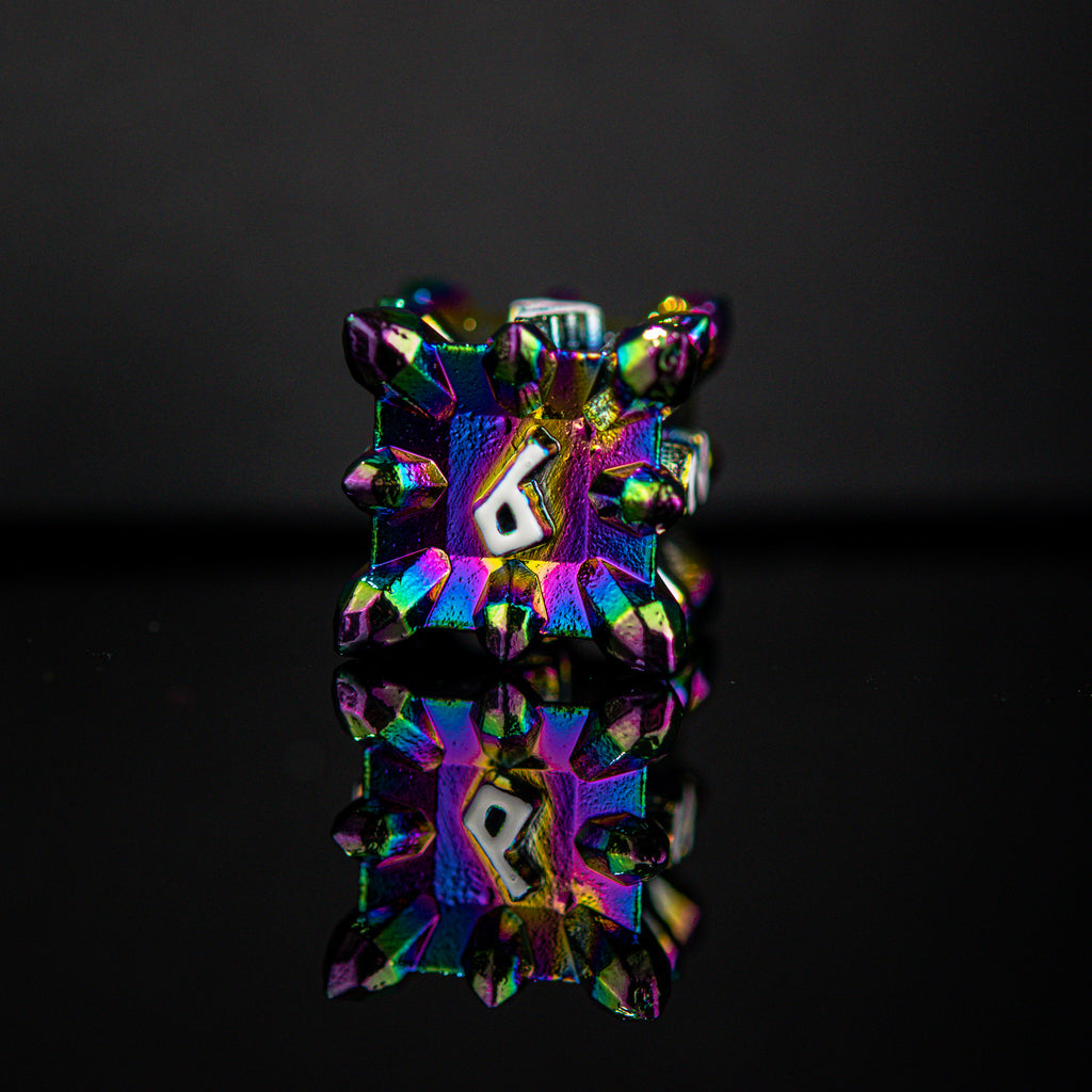 A set of metal dnd dice with embossed white numbers, featuring an iridescent oil slick, asteroid-like finish, displayed on a reflective surface.