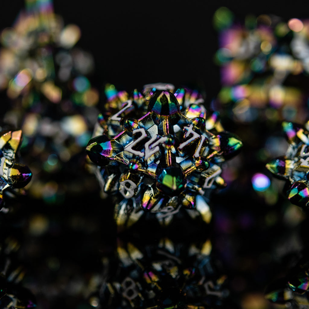 A set of metal dnd dice with embossed white numbers, featuring an iridescent oil slick, asteroid-like finish, displayed on a reflective surface.
