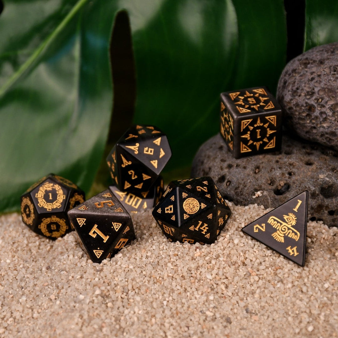 A set of black dice with gold Aztec patterns