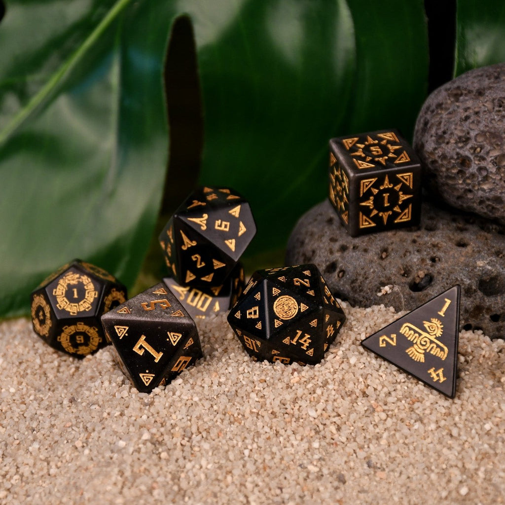 A set of black dice with gold Aztec patterns