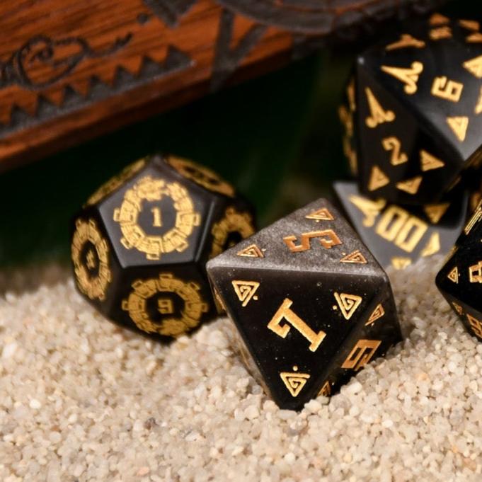 A set of black dice with gold Aztec patterns
