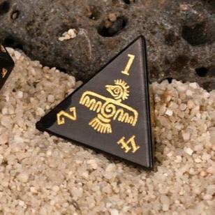 A set of black dice with gold Aztec patterns