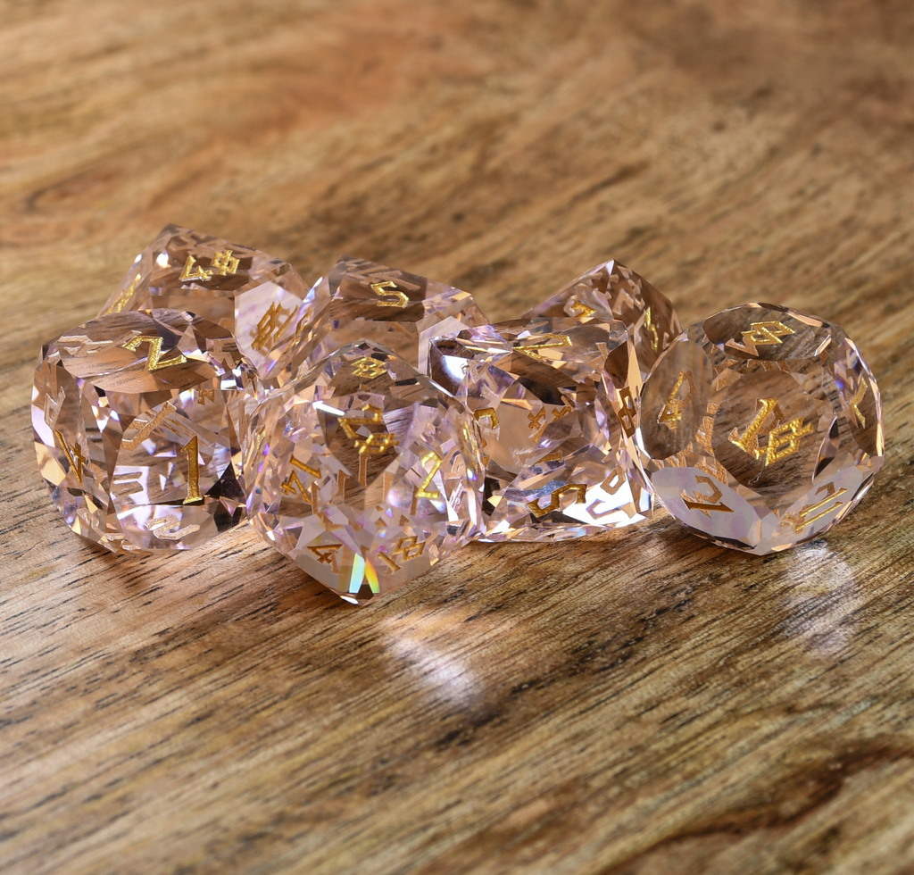 Baby Pink Topaz Multifaceted Glass Dice with gold numbering on wooden surface. 