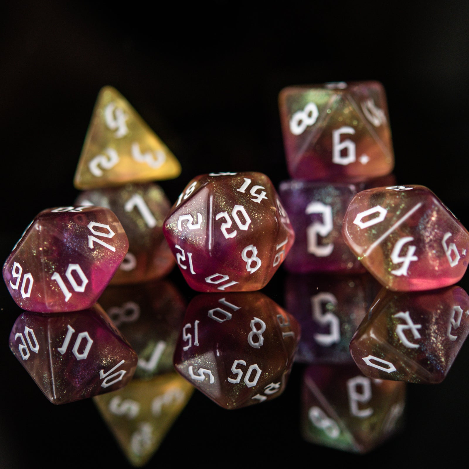 A set of multicolored orange and yellow acrylic dnd dice with engraved white numbers, displayed on a reflective surface.