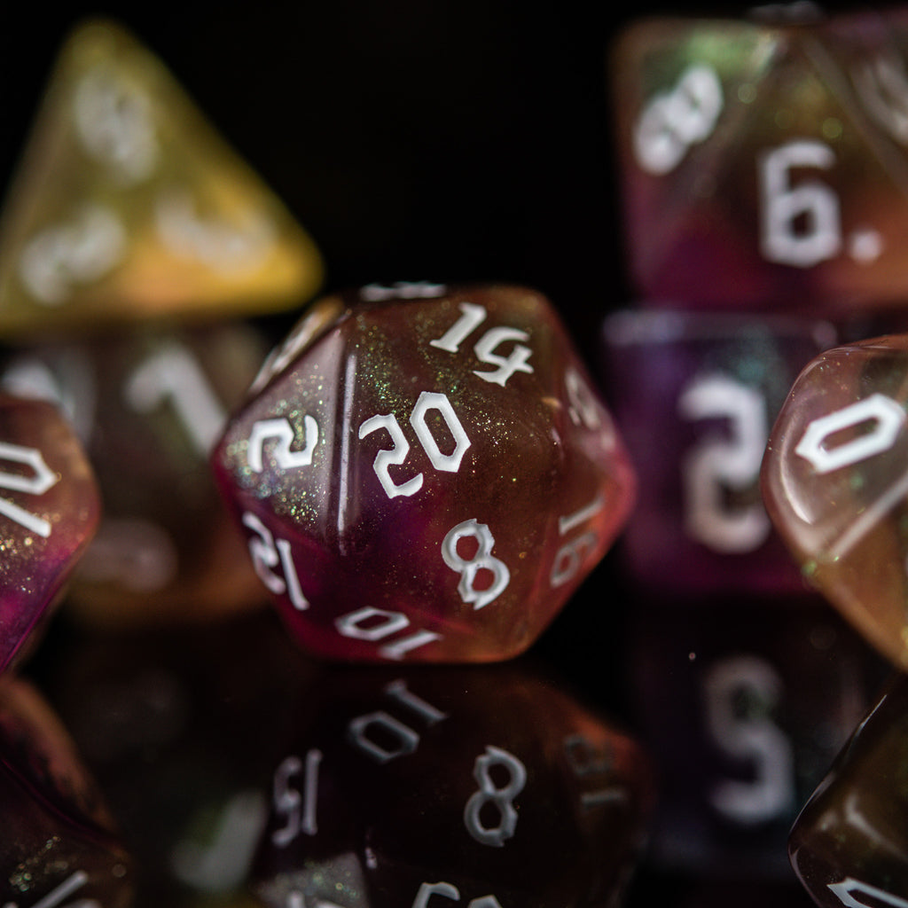 A set of multicolored orange and yellow acrylic dnd dice with engraved white numbers, displayed on a reflective surface.