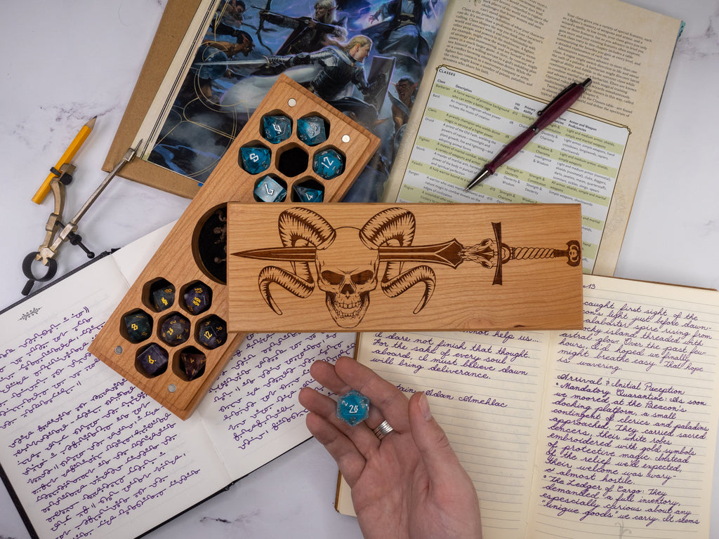 Wooden dice tray with engraved design on a surface with books and papers.