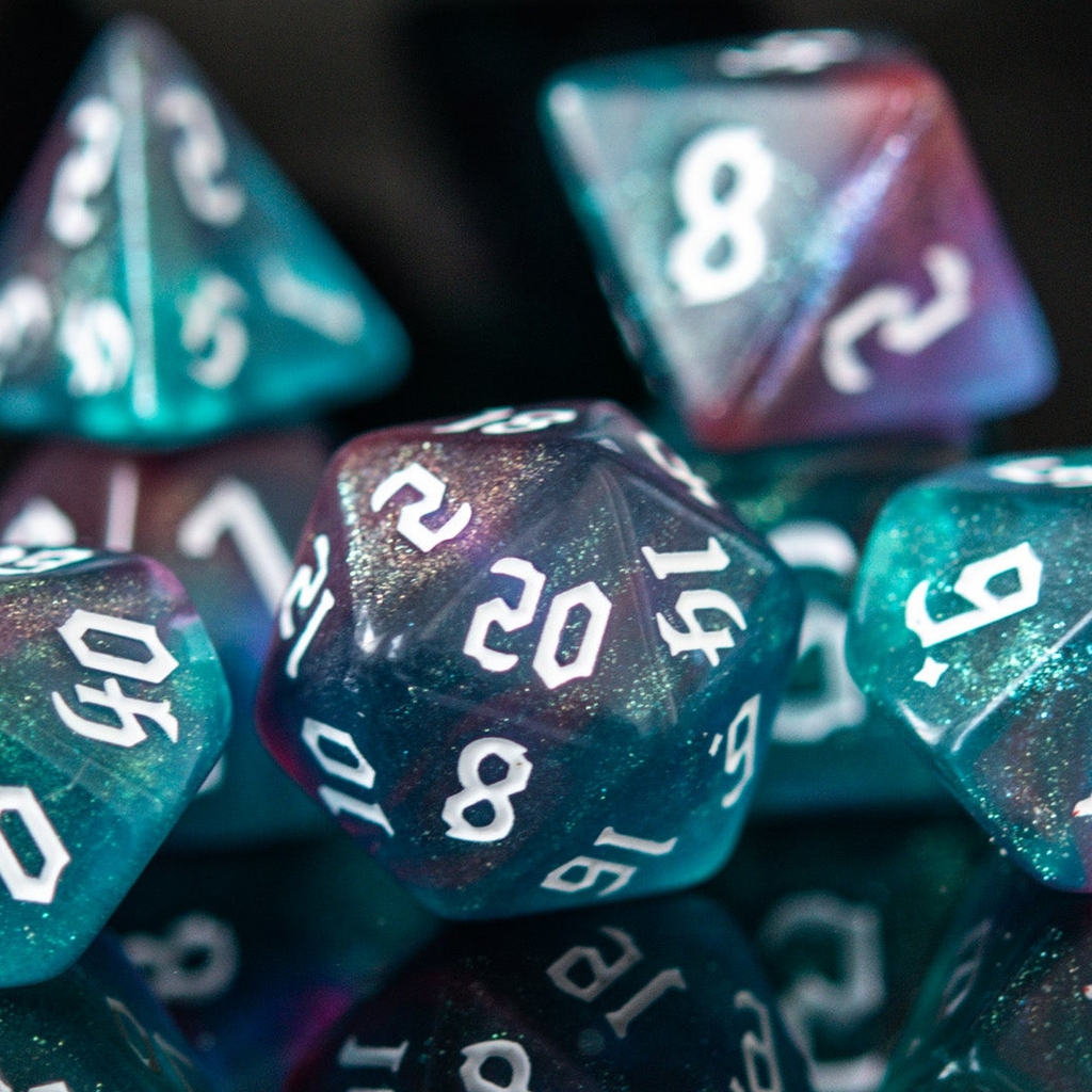 A set of multicolored acrylic dice with engraved numbers, displayed on a reflective surface.