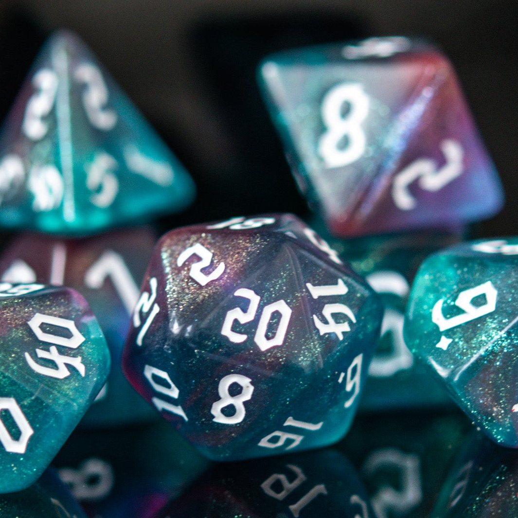 A set of multicolored acrylic dice with engraved numbers, displayed on a reflective surface.