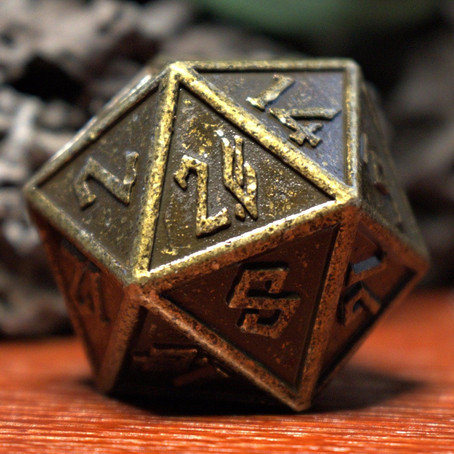 A close-up of a bronze-colored metal D20 dice with embossed numbers, placed on a wooden surface.