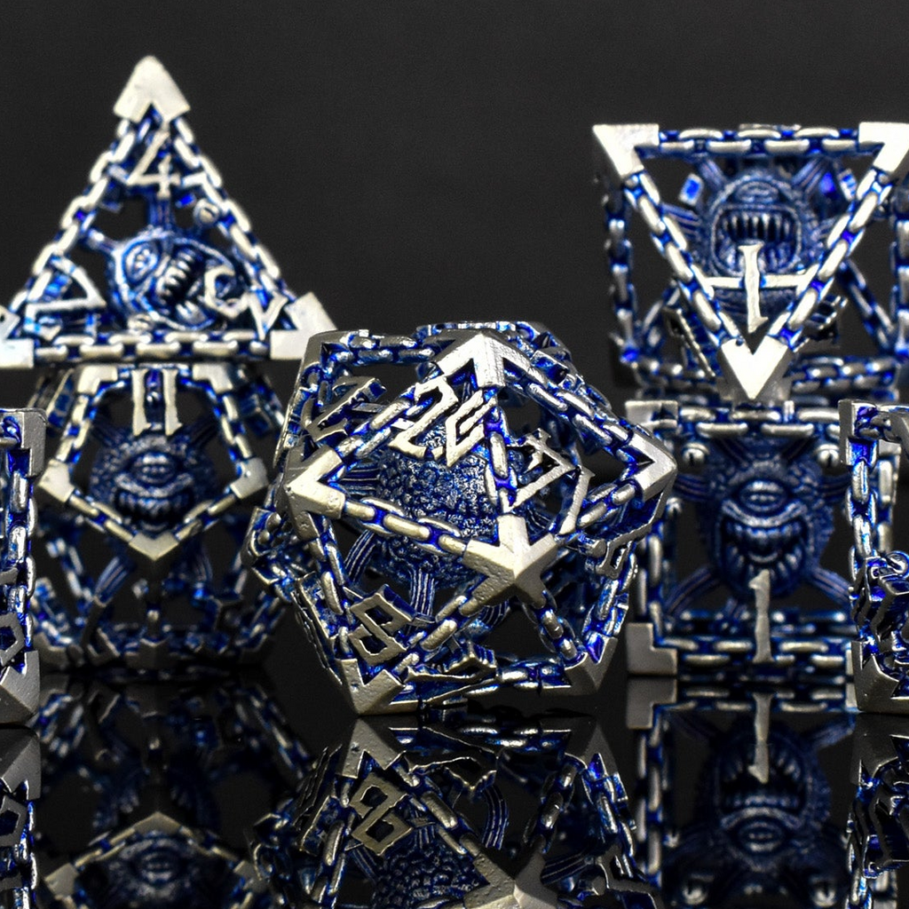 A set of hollow metal dice in blue and silver colors with embossed numbers, reflecting on a dark surface.