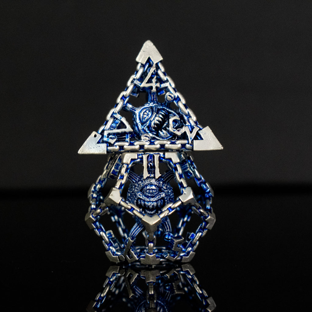 A set of hollow metal dice in blue and silver colors with embossed numbers, reflecting on a dark surface.