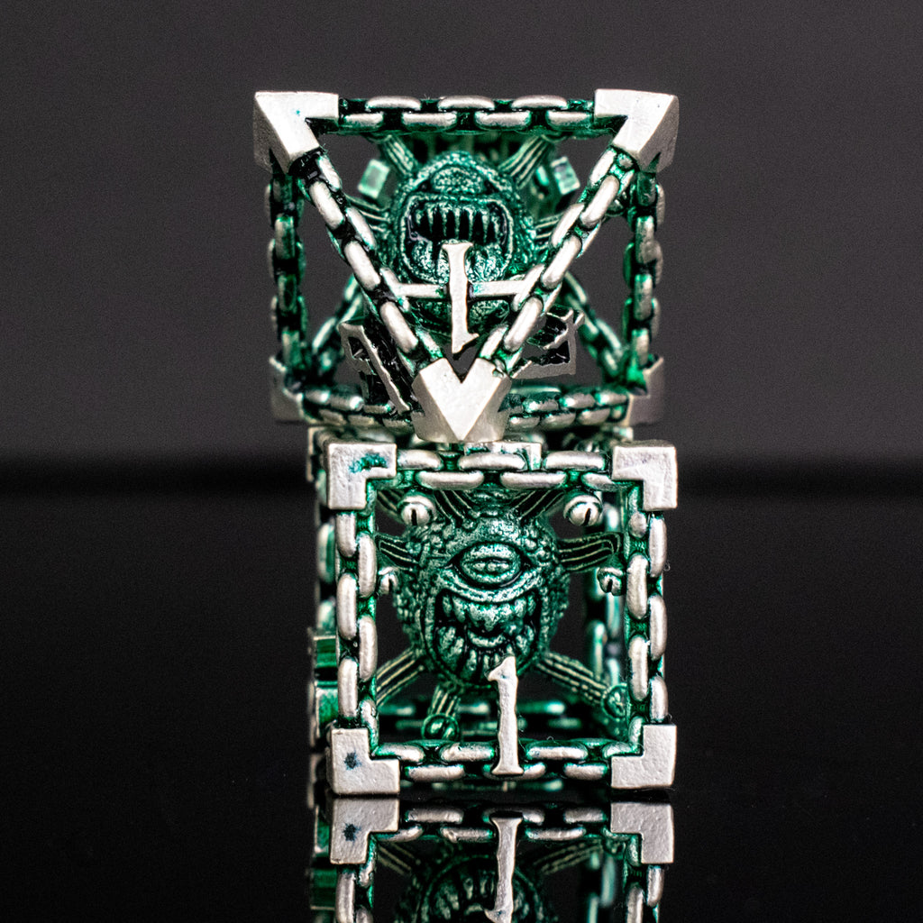 A set of hollow metal dice in green and silver colors with embossed numbers, reflecting on a black surface.