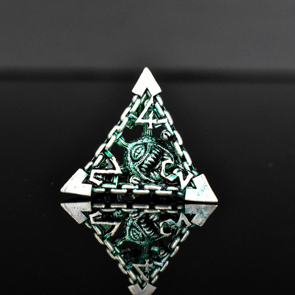 A set of hollow metal dice in green and silver colors with embossed numbers, reflecting on a black surface.