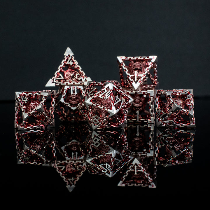 A set of hollow metal dice in red and silver, including various shapes such as a d4, d6, d8, d10, d12, and d20, displayed on a reflective surface.