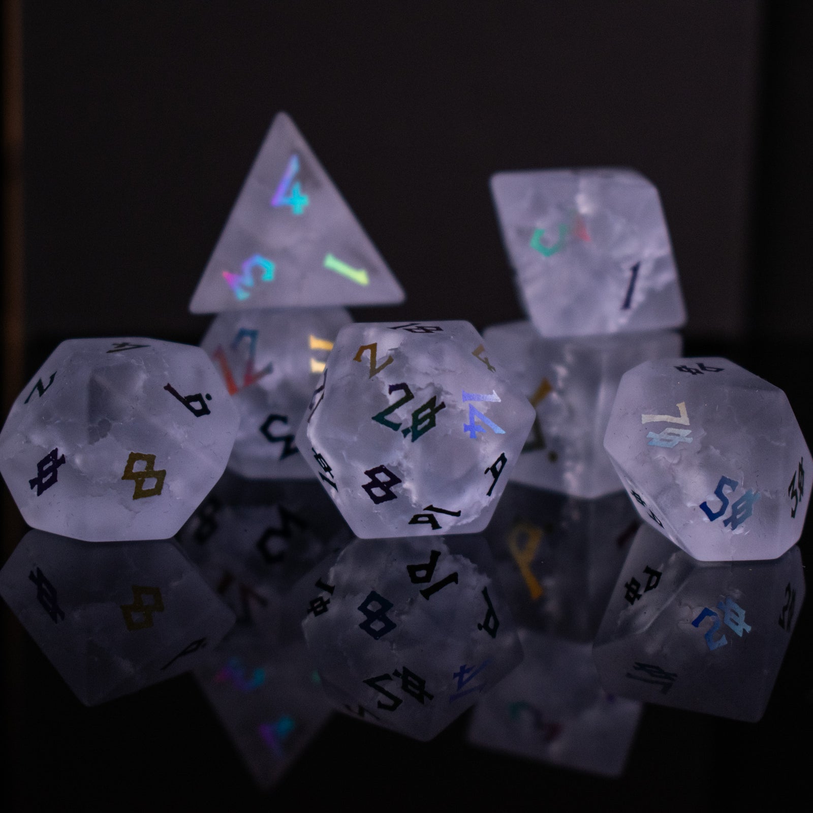 A collection of hand-carved, clear lavender glass dice with engraved numbers, illuminated by a light, displaying a Shattered Glass effect.