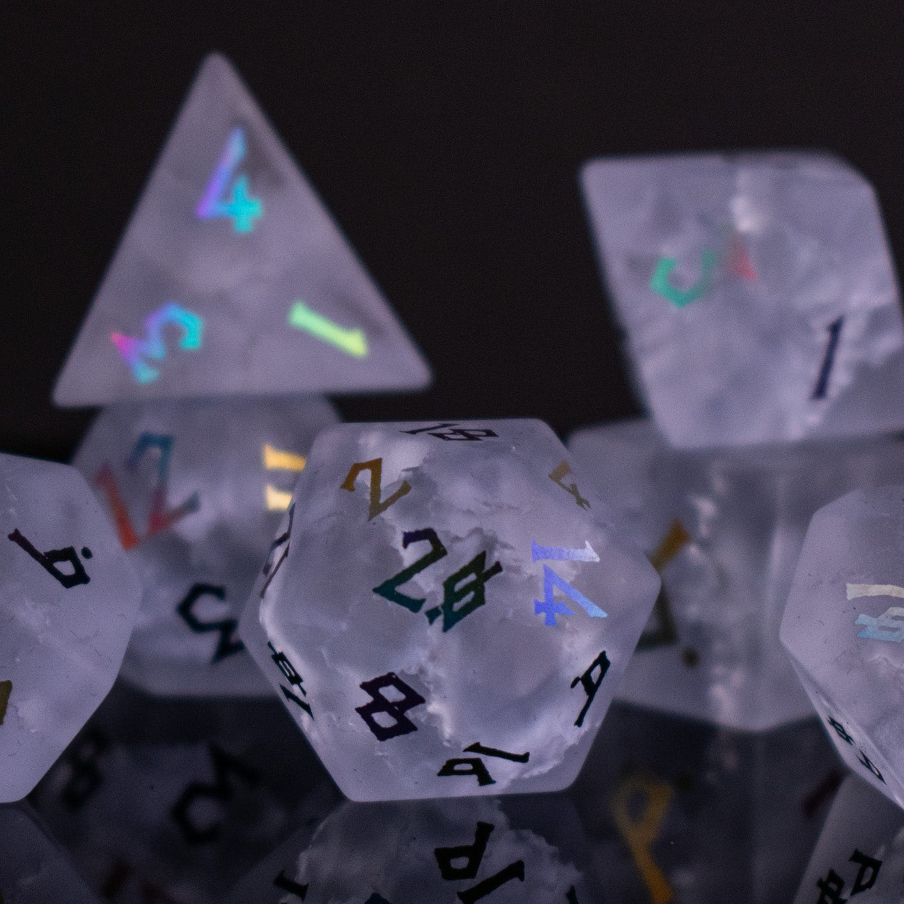 A collection of hand-carved, clear lavender glass dice with engraved numbers, illuminated by a light, displaying a Shattered Glass effect.