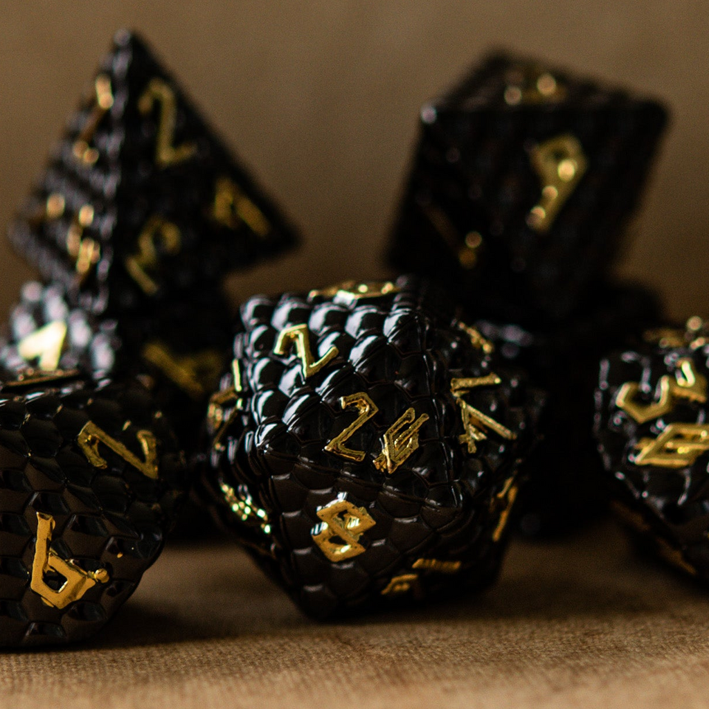 A set of black metal dice with embossed numbers, including various shapes such as a d4, d6, d8, d10, d12, and d20, displayed on a textured surface.