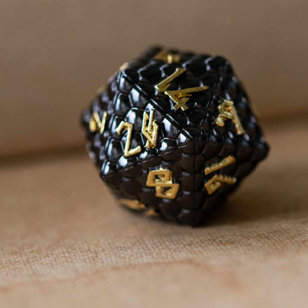 black metal d20 with dragon scale texture dnd die with gold numbering