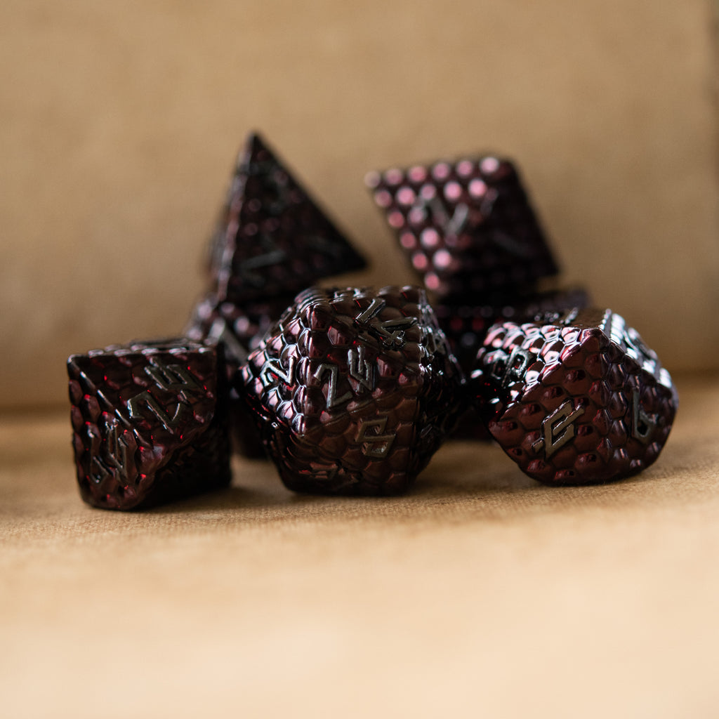 A set of metal dragons egg texture dice in dark red colors with embossed numbers, including various shapes such as a d4, d6, d8, d10, d12, and d20.