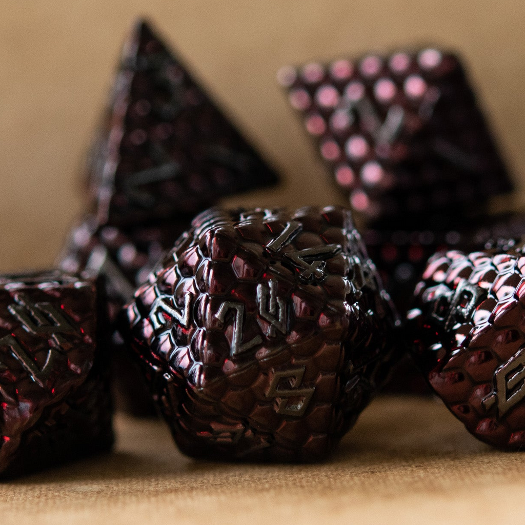 A set of metal dragons egg texture dice in dark red colors with embossed numbers, including various shapes such as a d4, d6, d8, d10, d12, and d20.
