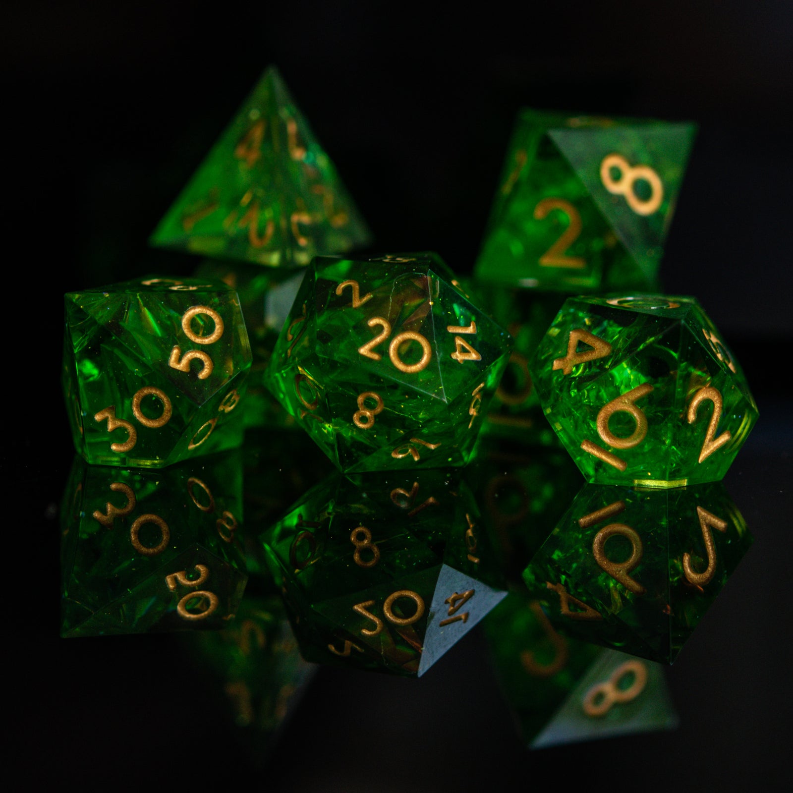 A set of green sharp-edged resin dice with gold engraved numbers, including various shapes such as a d4, d6, d8, d10, d12, and d20.