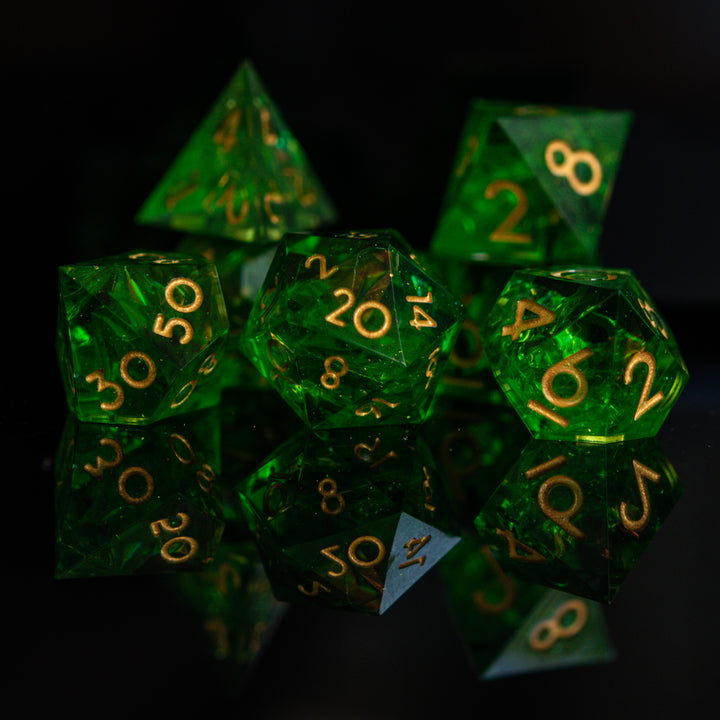 A set of green sharp-edged resin dice with gold engraved numbers, including various shapes such as a d4, d6, d8, d10, d12, and d20.