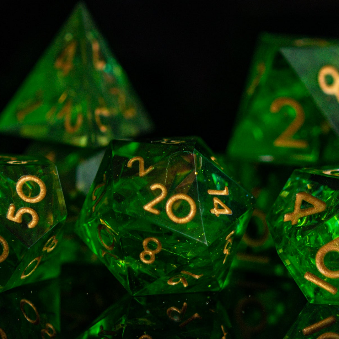 A set of green sharp-edged resin dice with gold engraved numbers, including various shapes such as a d4, d6, d8, d10, d12, and d20.