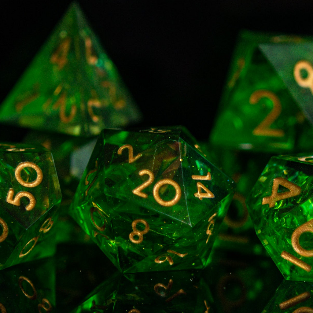 A set of green sharp-edged resin dice with gold engraved numbers, including various shapes such as a d4, d6, d8, d10, d12, and d20.
