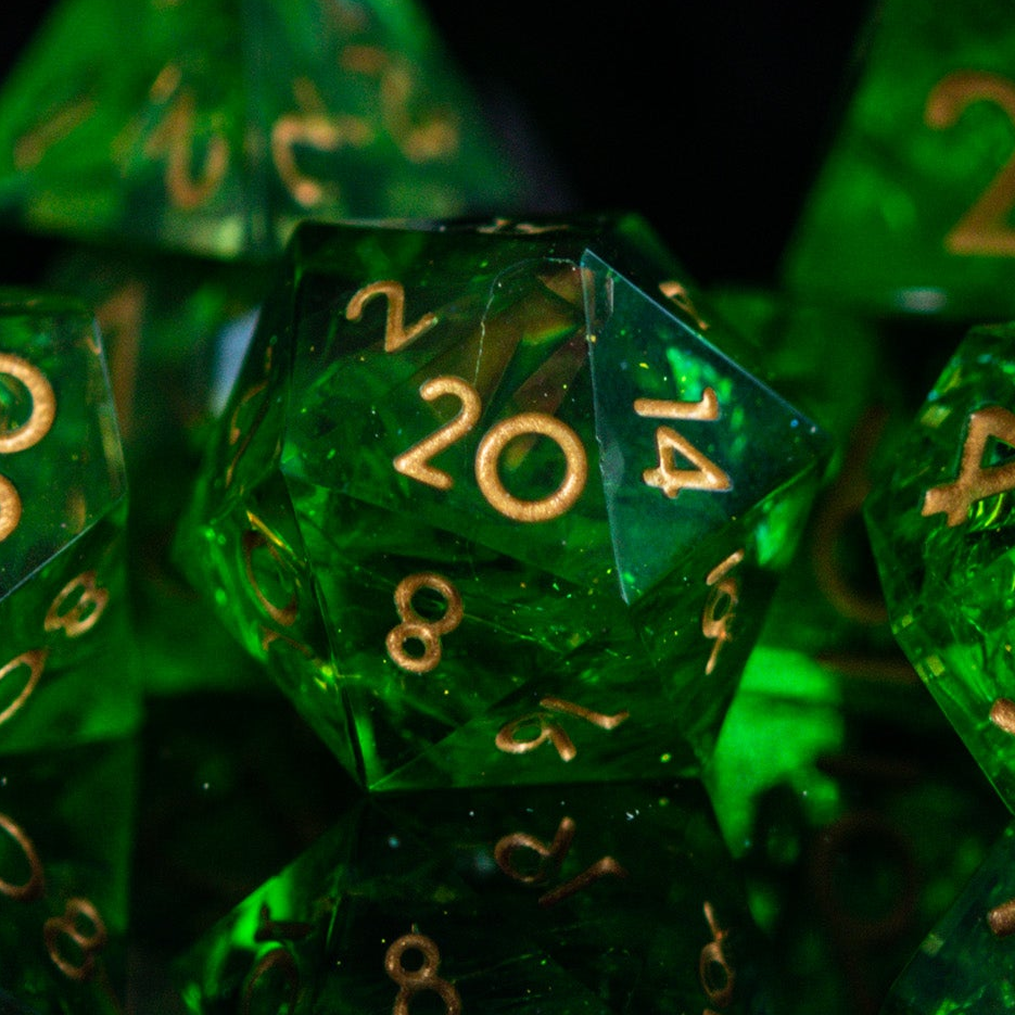 A set of green sharp-edged resin dice with gold engraved numbers, including various shapes such as a d4, d6, d8, d10, d12, and d20.