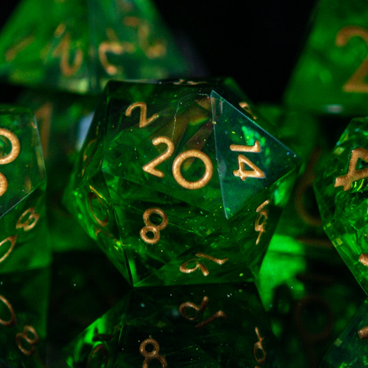A set of green sharp-edged resin dice with gold engraved numbers, including various shapes such as a d4, d6, d8, d10, d12, and d20.