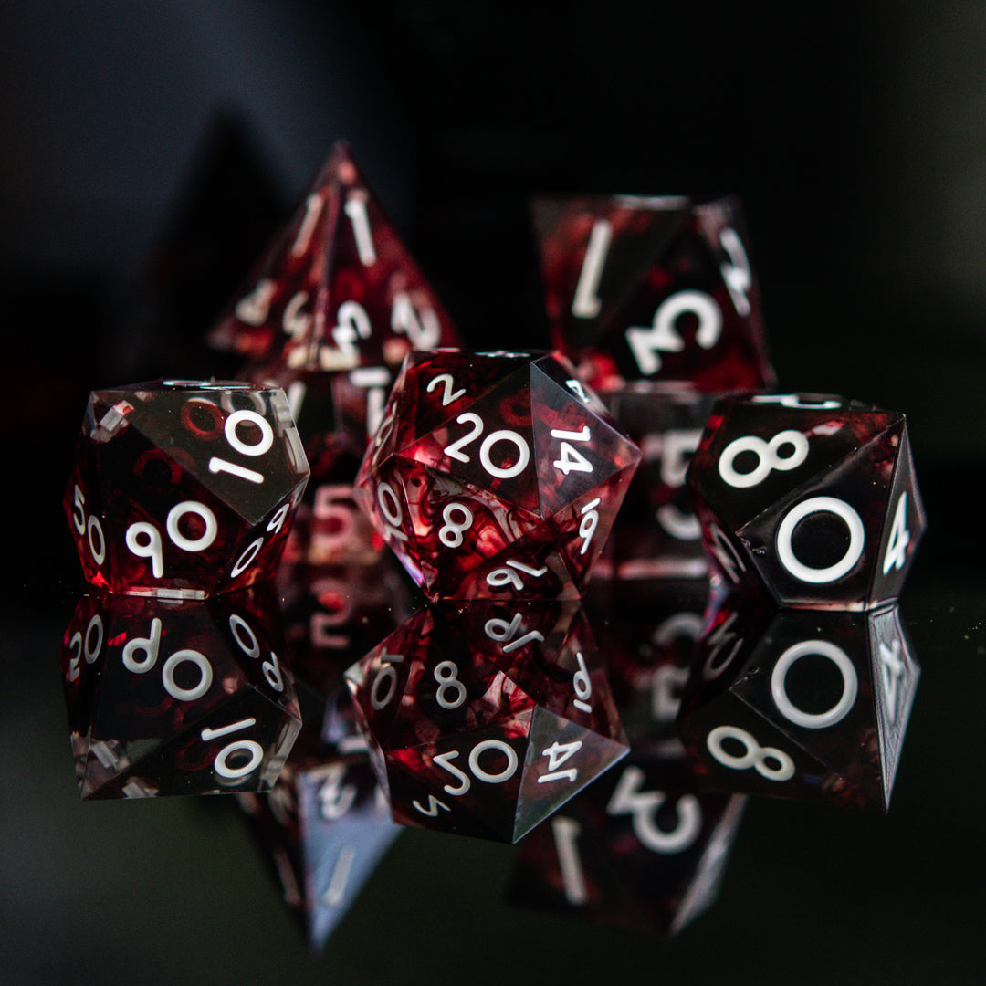 A set of polyhedral sharp edge resin clear dice with blood red running through and white numbering for tabletop games and board games