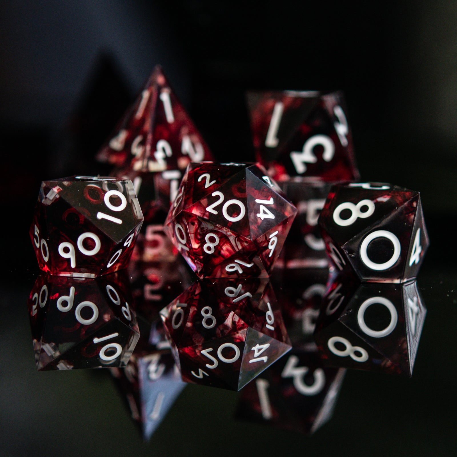 A set of polyhedral sharp edge resin clear dice with blood red running through and white numbering for tabletop games and board games