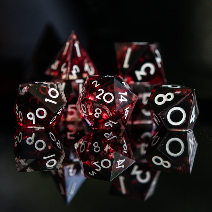 A set of polyhedral sharp edge resin clear dice with blood red running through and white numbering for tabletop games and board games