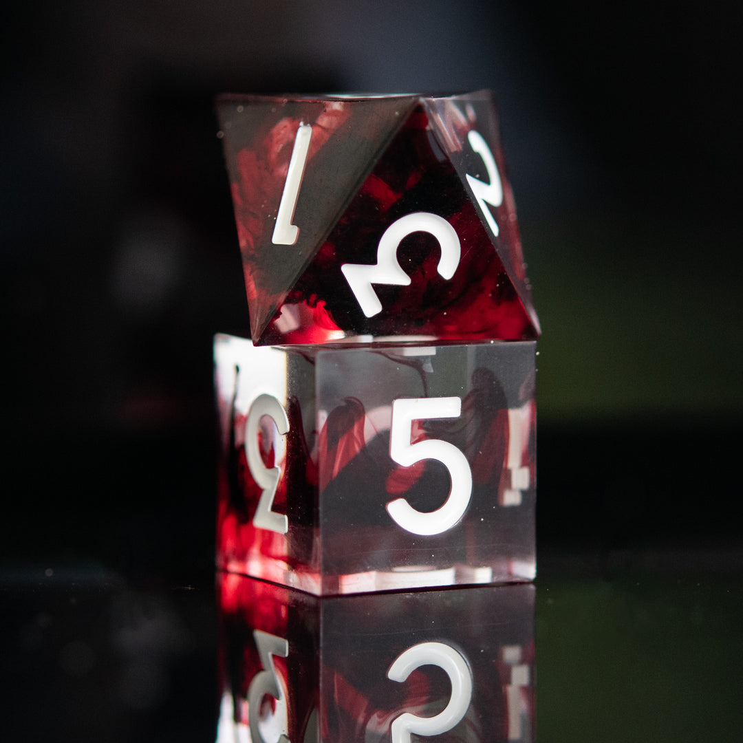 A set of polyhedral sharp edge resin clear dice with blood red running through and white numbering for tabletop games and board games