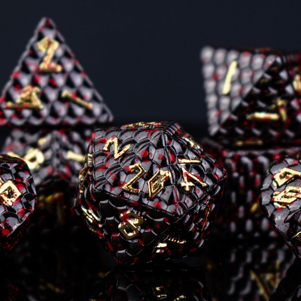A set of solid metal black dragon scale textured polyhedral dnd dice splattered with blood with gold numbers