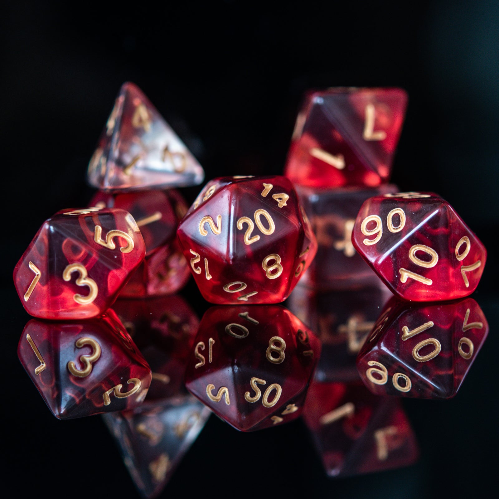 A set of red acrylic dice with engraved gold numbers