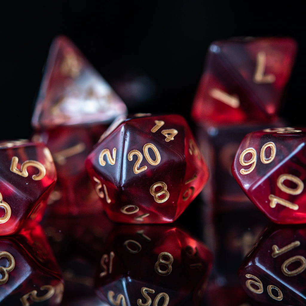 A set of red acrylic dice with engraved gold numbers