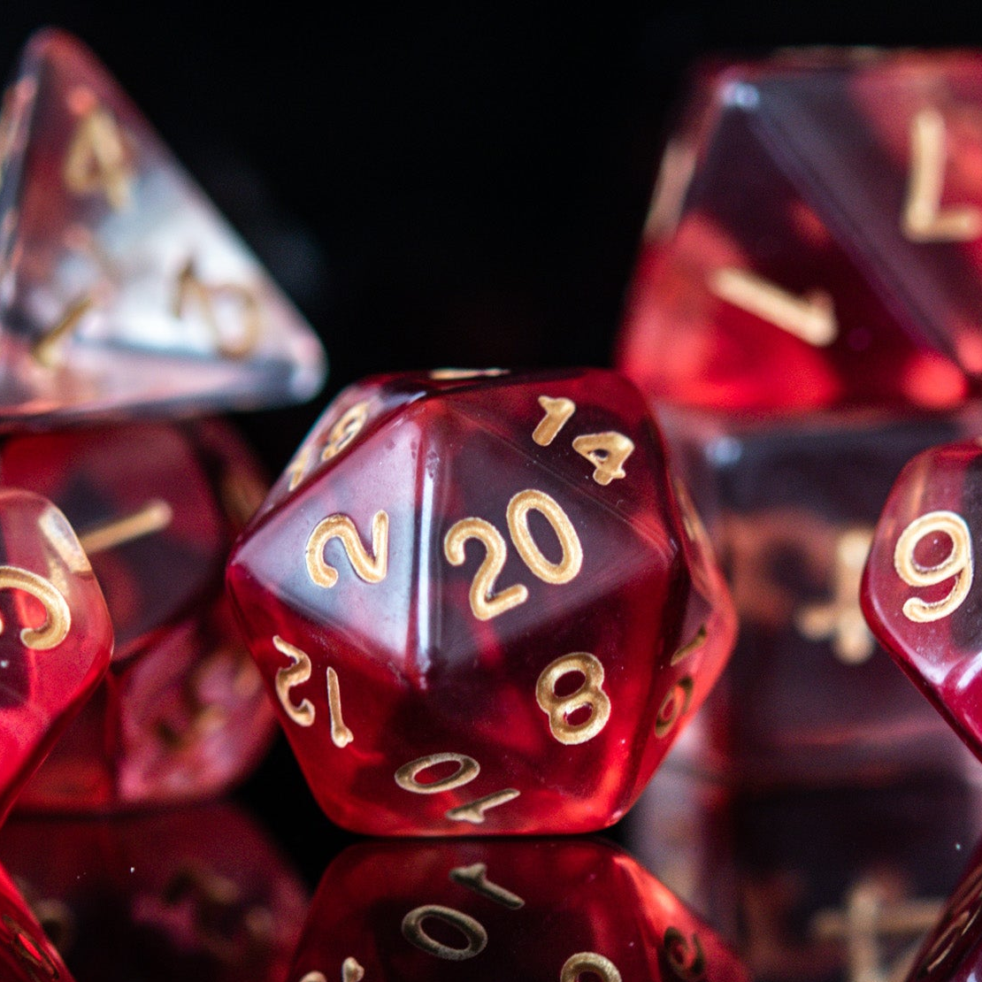 A set of red acrylic dice with engraved gold numbers