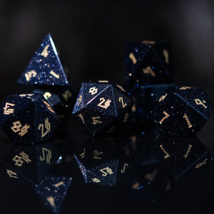 A set of hand-carved blue sandstone dice with gold numbers, reflecting a sparkling effect similar to stars.